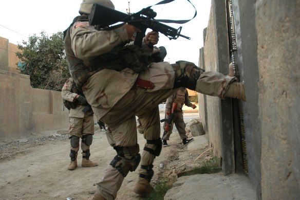 US soldiers kick in a door as they raid houses in southern Samarra, Iraq in 2004.