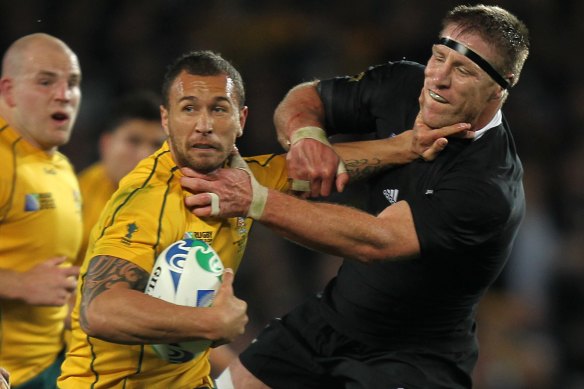 Brad Thorn, playing for the All Blacks, grapples with Wallaby and Reds player Quade Cooper.
