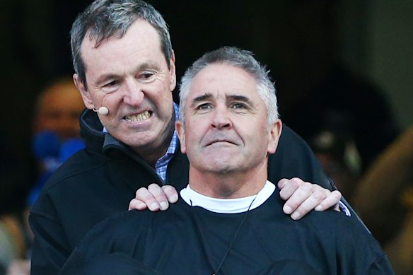 Neale Daniher pushes Brisbane Lions coach Chris Fagan – dressed as “the Reverend” – down the slide at the MCG.