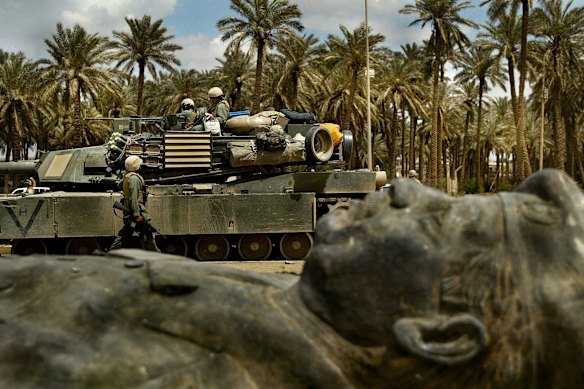 Un'unità corazzata americana passa davanti a una delle tante statue cadute dell'ex dittatore iracheno Saddam Hussein, a Baghdad nel 2003.
