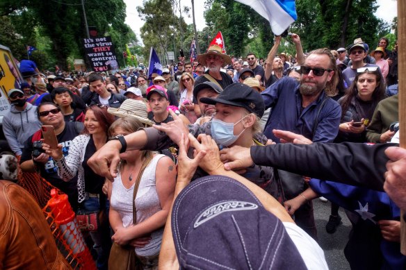 People in the crowd attempt to prevent a young man from throwing objects at Craig Kelly during the anti-vaccine mandate rally in Melbourne on Saturday.