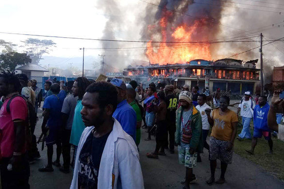 People gather as shops burn in the background during a protest in Wamena in Papua province, Indonesia, on Monday.