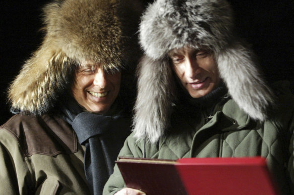 Russian President Vladimir Putin, right, presents a book about his rural lodge Zavidovo to Silvio Berlusconi in 2003.