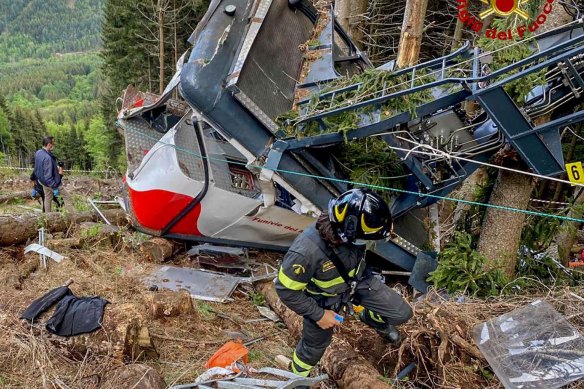 Rescuers work by the wreckage of a cable car after it crashed to the ground.
