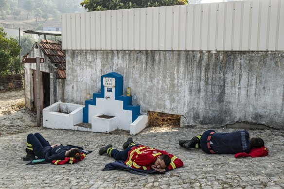 Firefighters are among the many essential workers we rely upon at all hours of the day. This photograph shows firefighters resting on the ground after spending the night battling wildfires in Portugal in 2022.