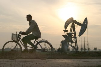A cyclist passes by oil wells at sunset at Sinopec's Shengli Oil Field in China's Shandong Province June 26, 2003. Oil refiners and traders in Asia may have shipped as much as 500,000 metric tons of gasoil, or diesel, in a month to South America and the U.S., where rising demand for the fuel is helping to sap excess supplies from the Asian region. Photographer: Kevin Lee / Bloomberg News man on bike / bicycle