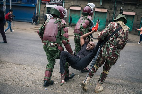 Police officers detain a protester in the central business district of Nairobi, Kenya.