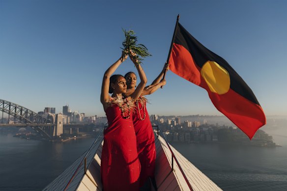 Abigail Delaney and Serene Dharpaloco Yunupingu [Dubs Yunupingu] from the Janawi Dance Clan, from the Darug nation, flying the Aboriginal flag on top of the largest sail of the Sydney Opera House.
