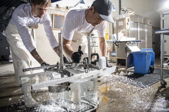 Staff at Bare Bones ice cutting large blocks of artisan ice.