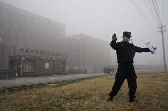 A security person moves journalists away from the Wuhan Institute of Virology after the WHO team arrived in February.