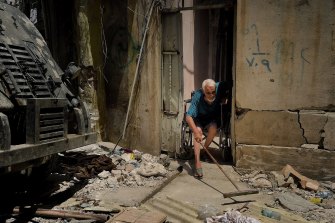 Abdulsalam Abdulqadir, 73, sweeps his porch as an air strike hits nearby in West Mosul, Iraq, in October 2017.
