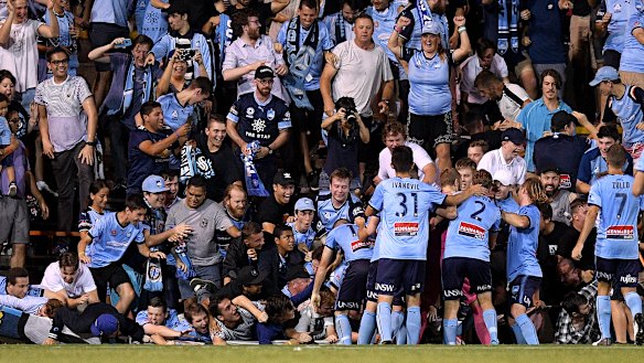 Fall season: Sydney fans sprawl onto the turf after the fence collapsed during celebrations for Cam Devlin's late sealer.