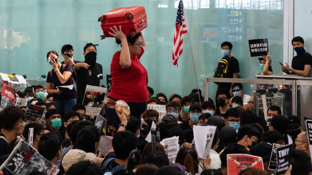 A traveller carries a suitcase on her head as she wades through sitting protesters at Hong Kong International Airport on Tuesday.