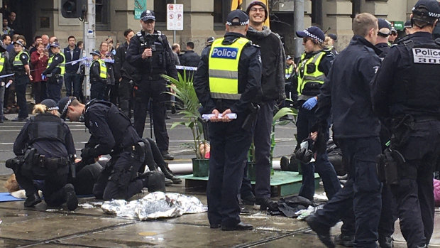 Police work to cut plastic pipes used by Extinction Rebellion climate activists to lock themselves together in Melbourne.