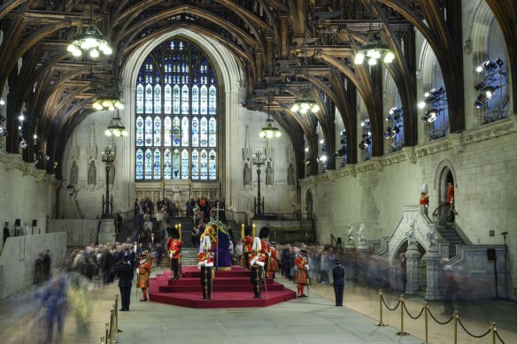 Members of the public file past the coffin of Queen Elizabeth II, draped in the Royal Standard with the Imperial State Crown and the Sovereign’s orb and sceptre, lying in state on the catafalque in Westminster Hall.