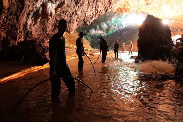 Thai rescue teams arrange water pumping system at the entrance to a flooded cave complex where the 12 boys and their soccer coach were trapped.