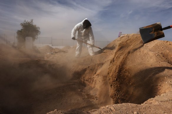 Frontline cemetery workers in full personal protective equipment bury a victim of COVID-19 at Suenos Eternos cemetery on November 21, 2020 in Ciudad Juarez, Mexico.