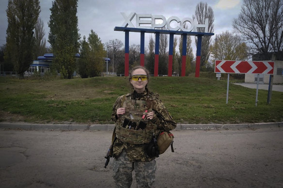 A Ukrainian female soldier poses for a photo against a Kherson sign in the background, in Kherson, on Friday.