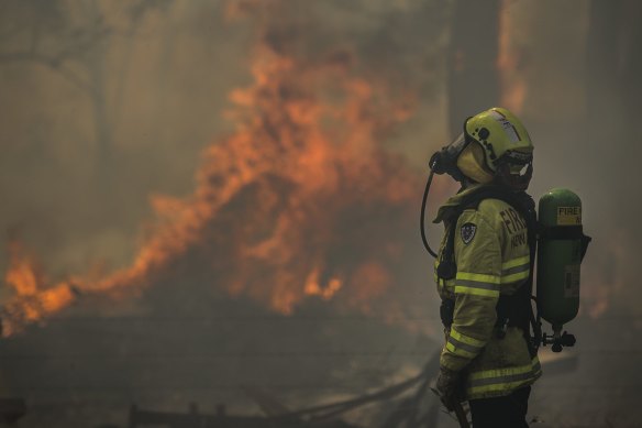 Firefighter Adam Brown from FRNSW protects properties along Glenthorne Rd in South Taree from an out of control bushfire.