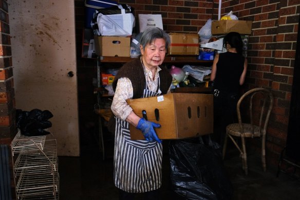 Sue Louey, 85, moves boxes at her flooded home in Maribyrnong.