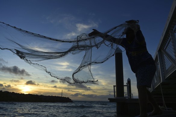 A fisherman, whose livelihood relies on his catch, casts his net from a boat off Hammond Island in the Torres Strait.