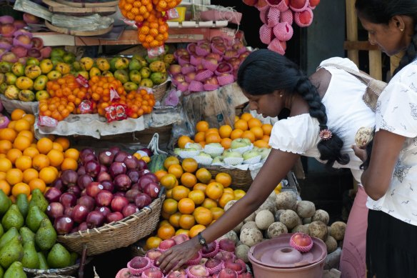 A woman selects apples at a produce stall in Galle, Sri Lanka.
