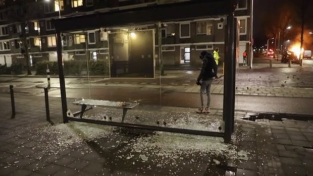 A person stands at a bus stop where the glass has been shattered after rioting, in Haarlem, Netherlands. 