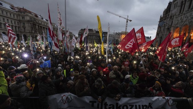 Anti-government demonstrators carry a banner reading "We protest against the slave bill" as they protest in front of the Parliament building at Kossuth square in  Budapest on  Saturday.