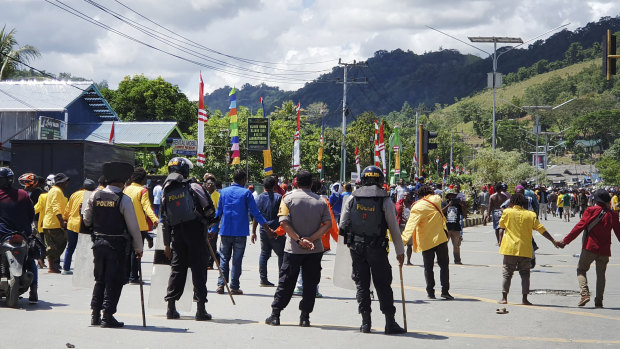 Police officers stand guard as protesters march during a rally in Abepura, Papua province, Indonesia.