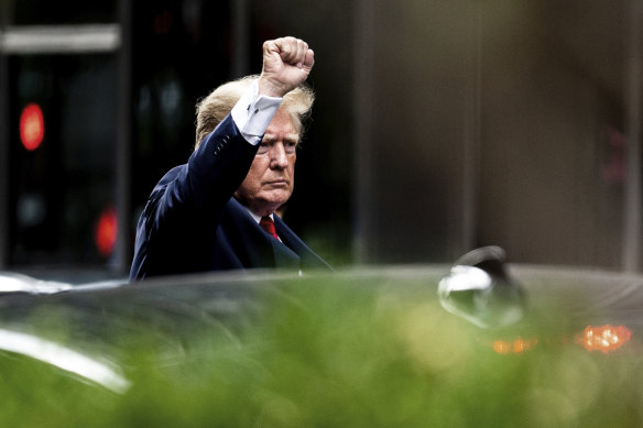 Donald Trump raises his fist as he makes his way to the New York attorney-general’s office for a deposition.
