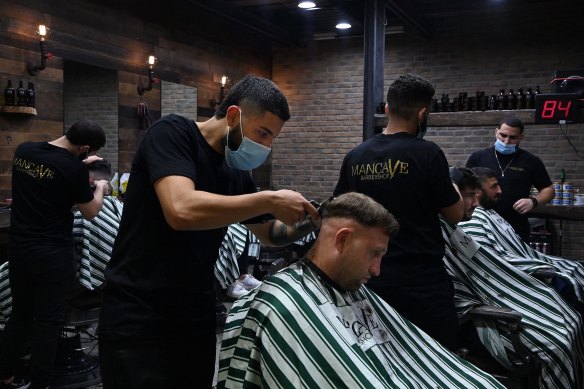 Mancave Barbershop barber Hardi Zahr (5th from right) cuts a customers hair in Westfield Bondi Junction shopping centre on the first day of relaxed COVID-19 restrictions for fully vaccinated people.