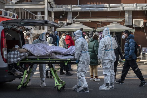 Medical workers wear PPE as they arrive with a patient on a stretcher at a fever clinic.