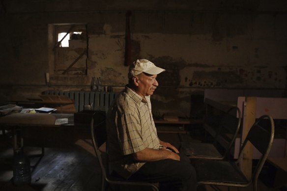 Ivan, 62, sits in the chair where he and his family sat while being held in the basement of a school for 25 days.