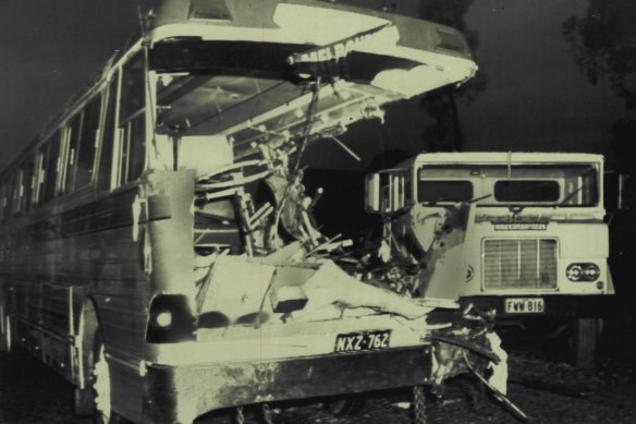 The wrecked tourist coach with the semi-trailer in the background. The impact sheared off the coach's left side.
