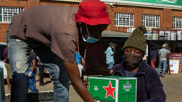 Workers load up outside the Sam Liquor Store in Thokoza township, near Johannesburg, South Africa, Monday, June 1, 2020.  Liquor stores reopened after being closed for over two months under lockdown restrictions.