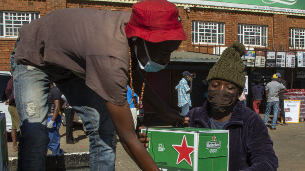 Workers load up outside the Sam Liquor Store in Thokoza township, near Johannesburg, South Africa, Monday, June 1, 2020.  Liquor stores reopened after being closed for over two months under lockdown restrictions.