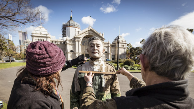 Now you see him: Liu Bolin's team works to camouflage him at the Royal Exhibition Building on Monday.   