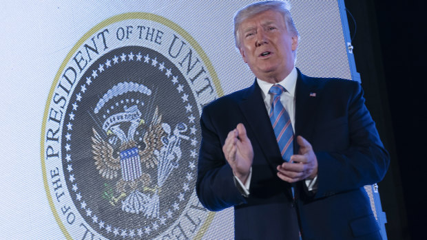 President Donald Trump stands in front of a doctored presidential seal on stage at the Turning Point USA student action summit.