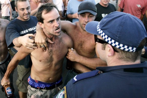 A man confronts police, holding a beer bottle during the Cronulla riots.