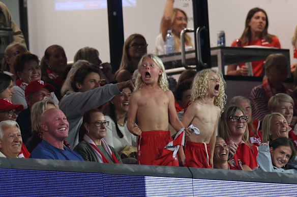 Former Swans player Barry Hall’s children celebrate a goal as Hall, bottom left, laughs.