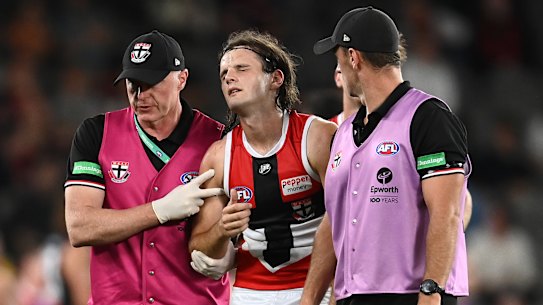 MELBOURNE, AUSTRALIA - MARCH 05: Hunter Clark of the Saints is helped from the ground by trainers during the AFL AAMI Community Series match between the Essendon 