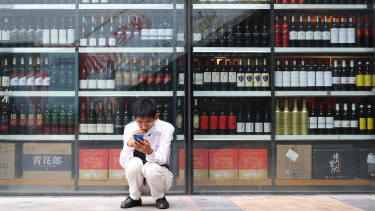 A man sits in front of a wine shop that sells Australian wines in eastern Beijing’s Tongzhou district. 