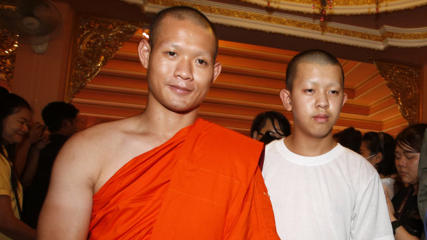 Monk Ekkapol Chanthawong walks with Pornchai Kamluang, right, a member of Wild Boars soccer team.