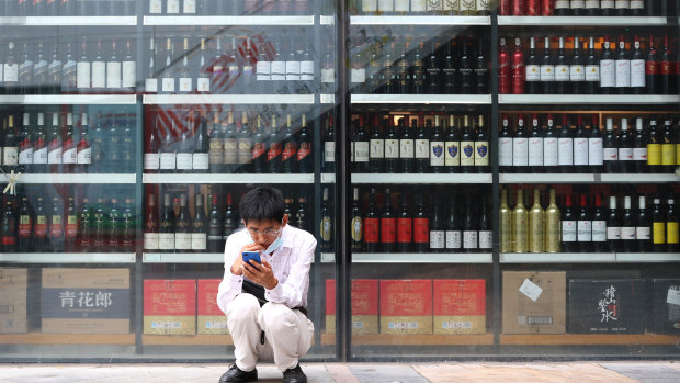 A man sits in front of a wine shop that sells Australian wines in eastern Beijing’s Tongzhou district. 