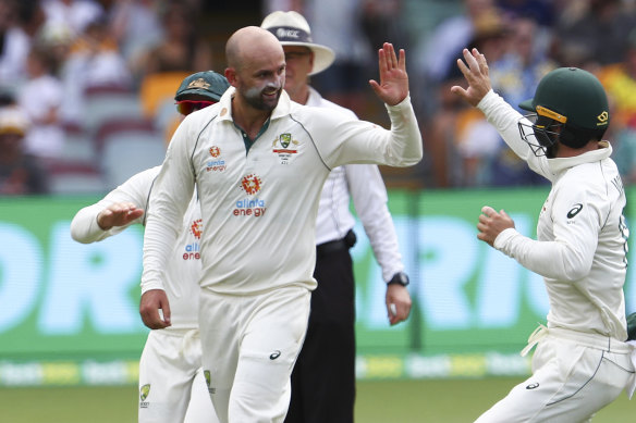 Australia’s Nathan Lyon, left, is congratulated by teammate Matthew Wade after taking the wicket of India’s Rohit Sharma during play on day two of the fourth cricket test between India and Australia at the Gabba, 