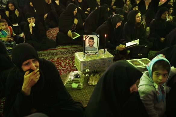 Women surround a framed photo of asylum seeker Reza Berati, during the memorial service held at the Al-Mahdi mosque in the Nabard neighbourhood in South East Tehran, Iran. 27th Feburary, 2014. Photo: Kate Geraghty