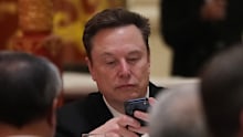 The Tesla chief appears captivated by his phone during the state dinner.