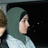 Janai Safar is escorted from the airport to the police station.
