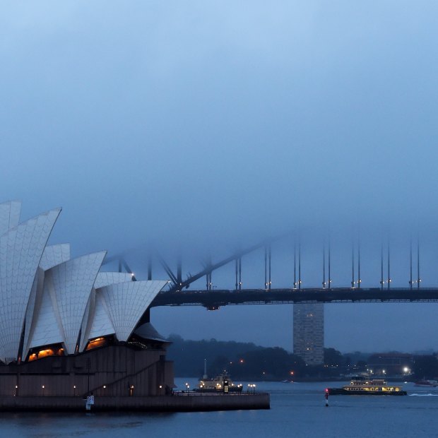 Fog and rain hang over the Opera House and Harbour Bridge.