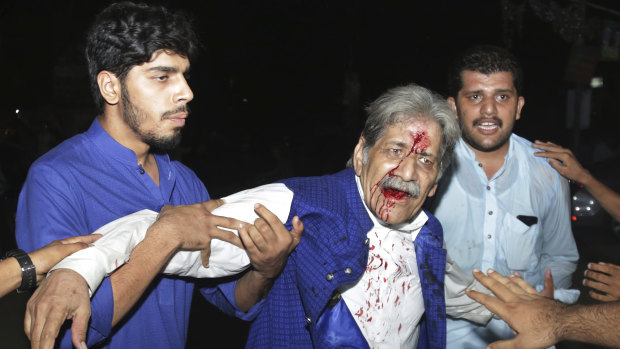 People hold an injured supporter of former prime minister Nawaz Sharif after a clash with police in Lahore, Pakistan, on Friday.